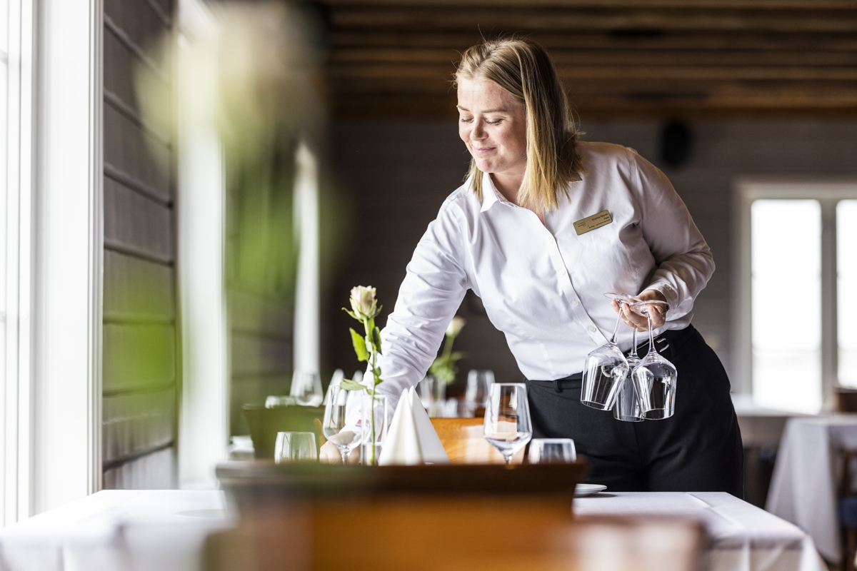 Servitør dekker bord på Finnøy Bryggehotell